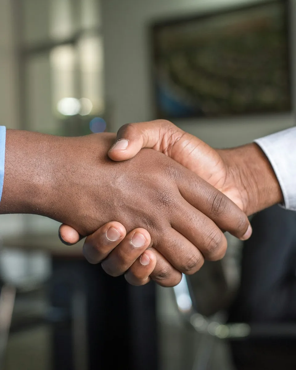 Two people shaking hands across a table in an office