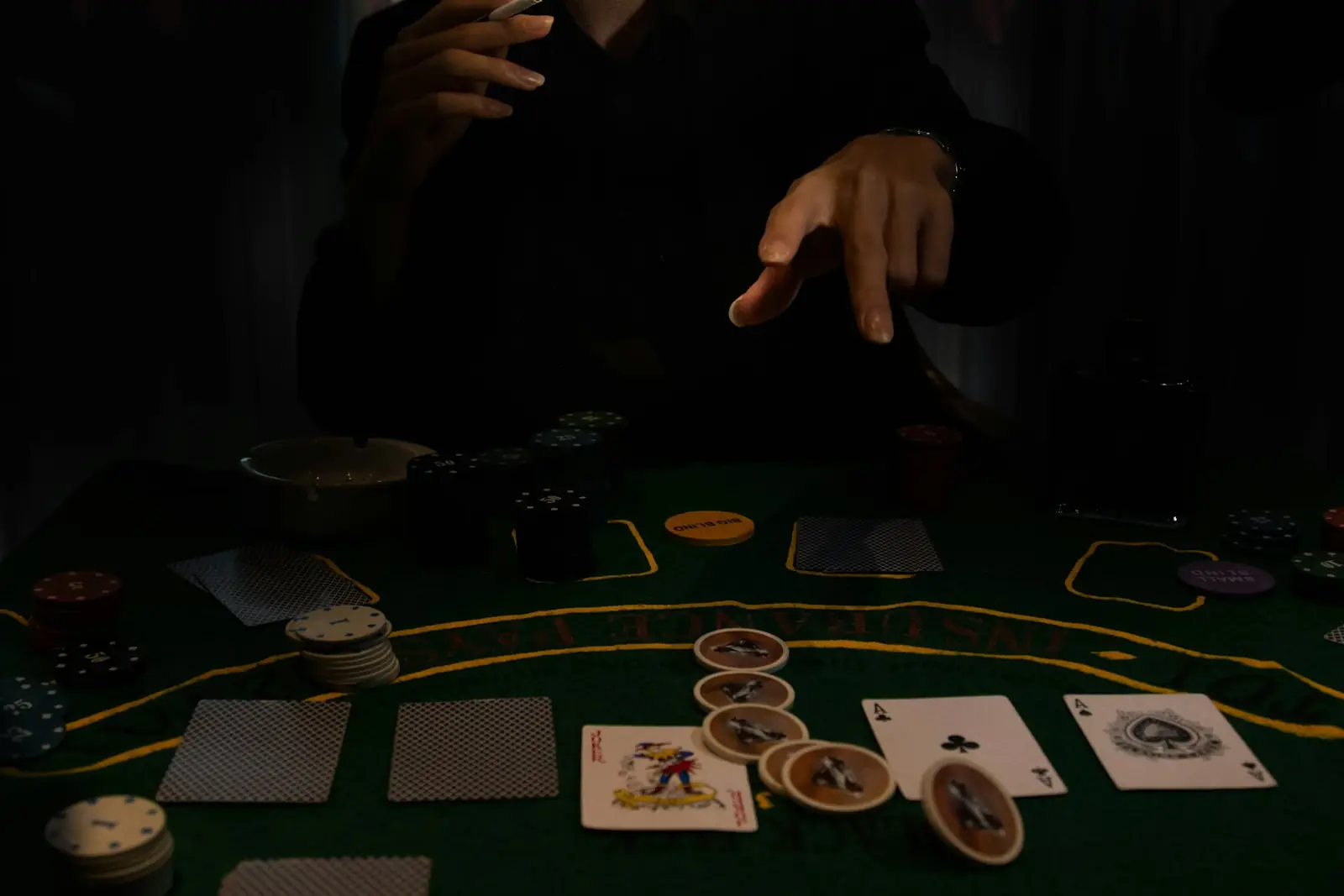 A hand over cards and chips on a dark casino table