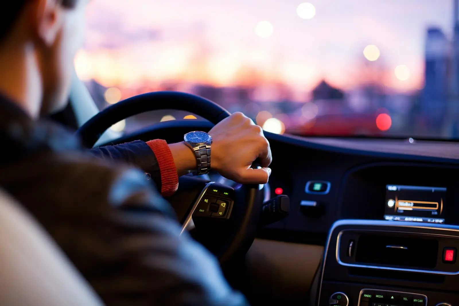 A driver's hands on the wheel at sunset