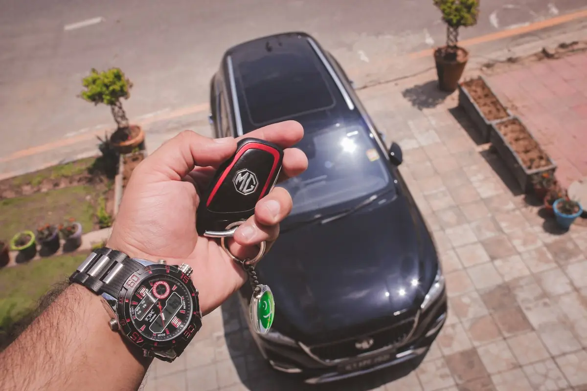 A hand holding a car key beside a car