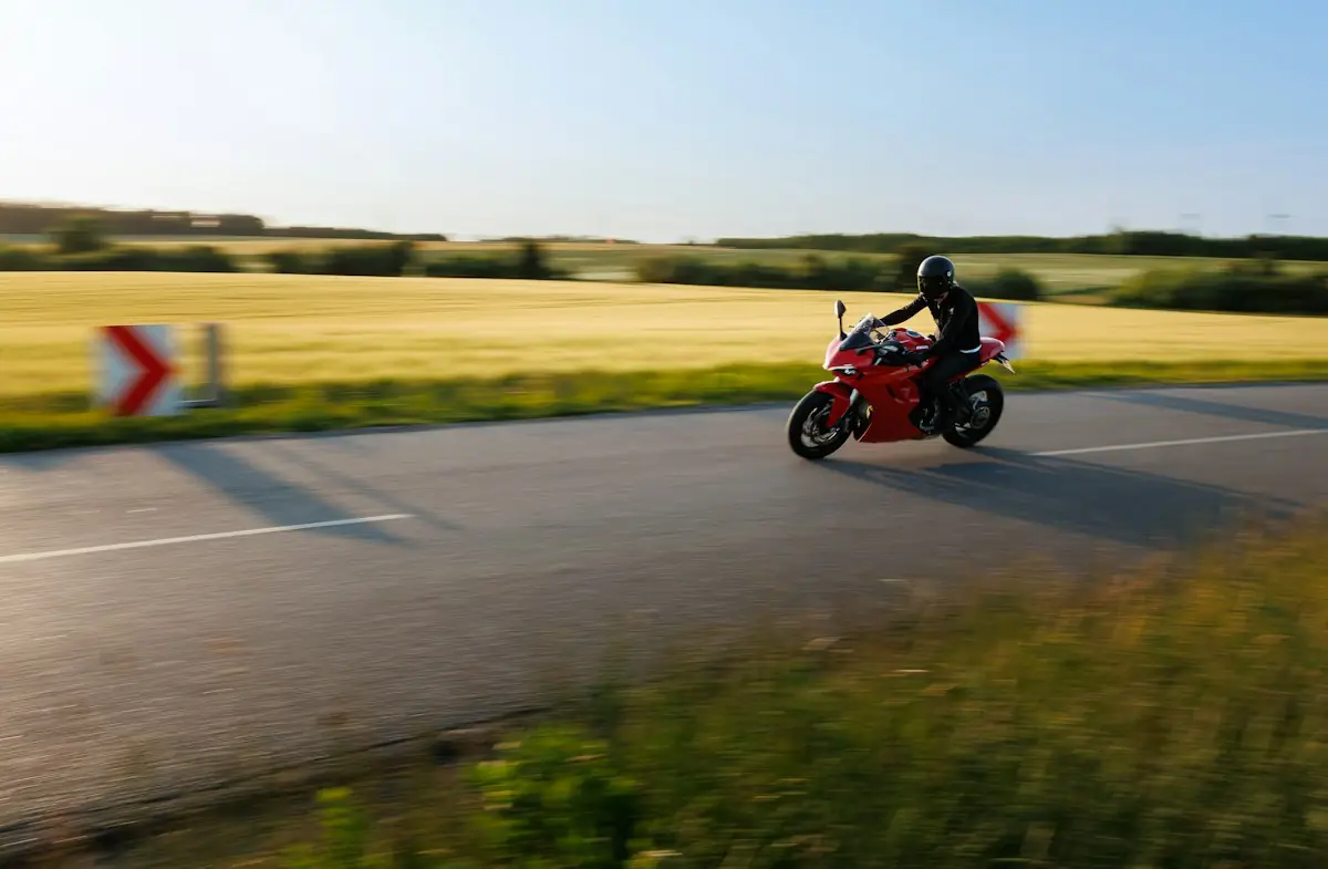 A motorcyclist on a red bike on a country road