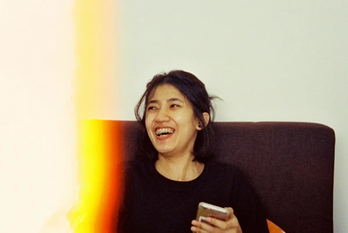 A woman laughing while holding her phone