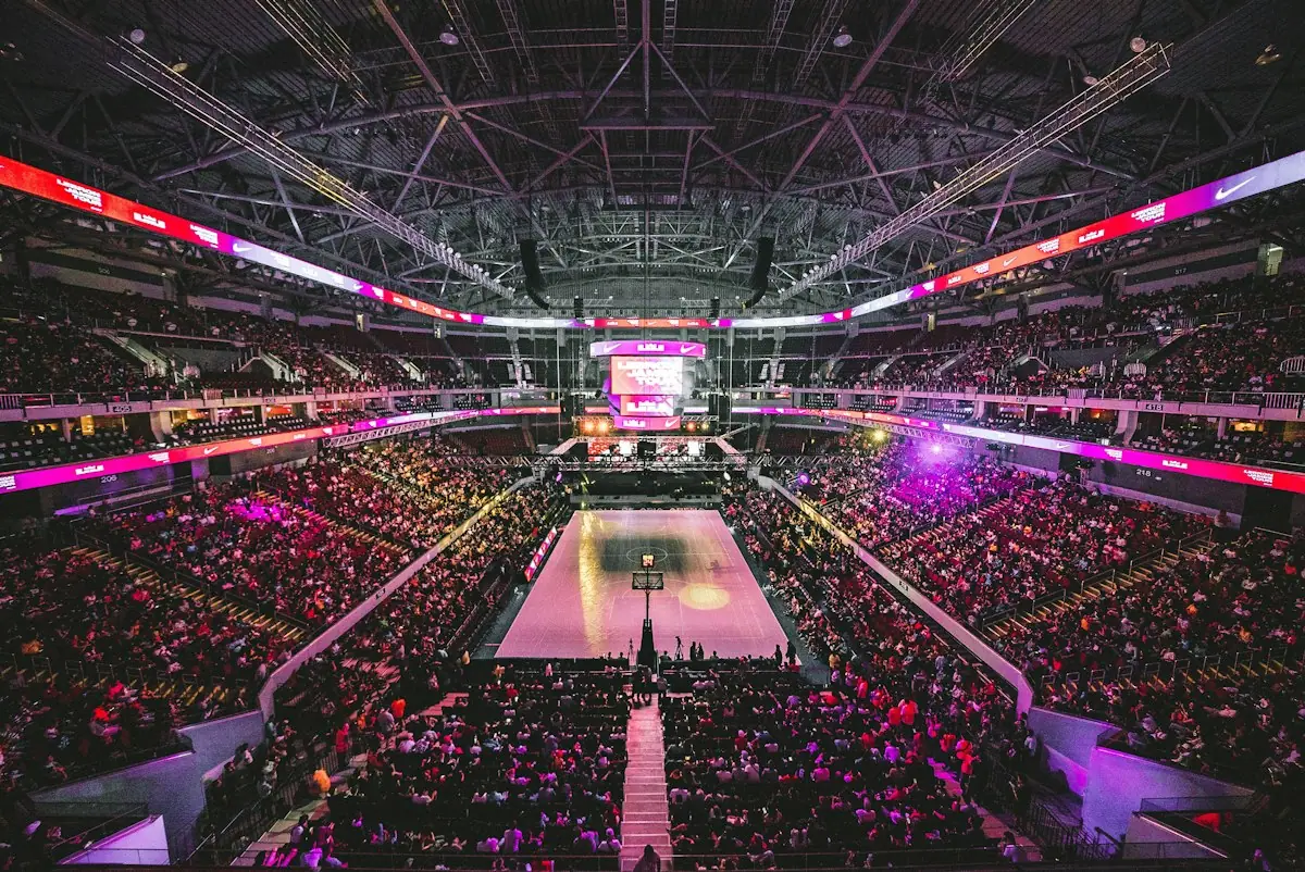 A packed esports arena lit in pink and purple