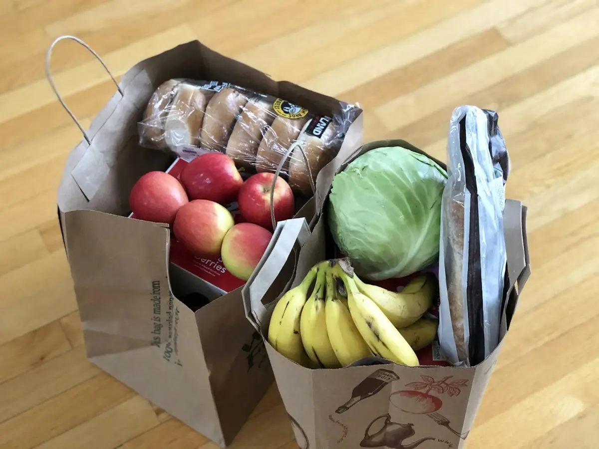 Paper grocery bags of apples, bananas and cabbage