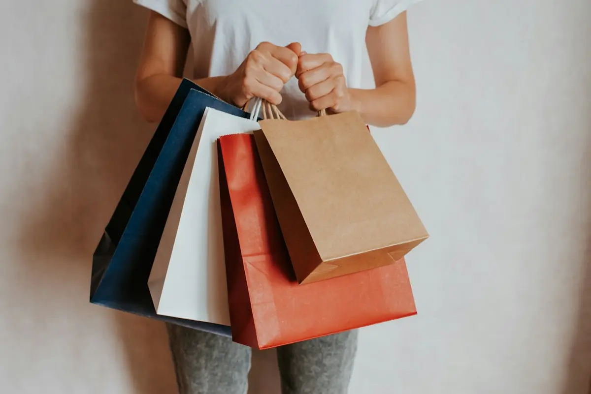 Hands holding colourful paper shopping bags