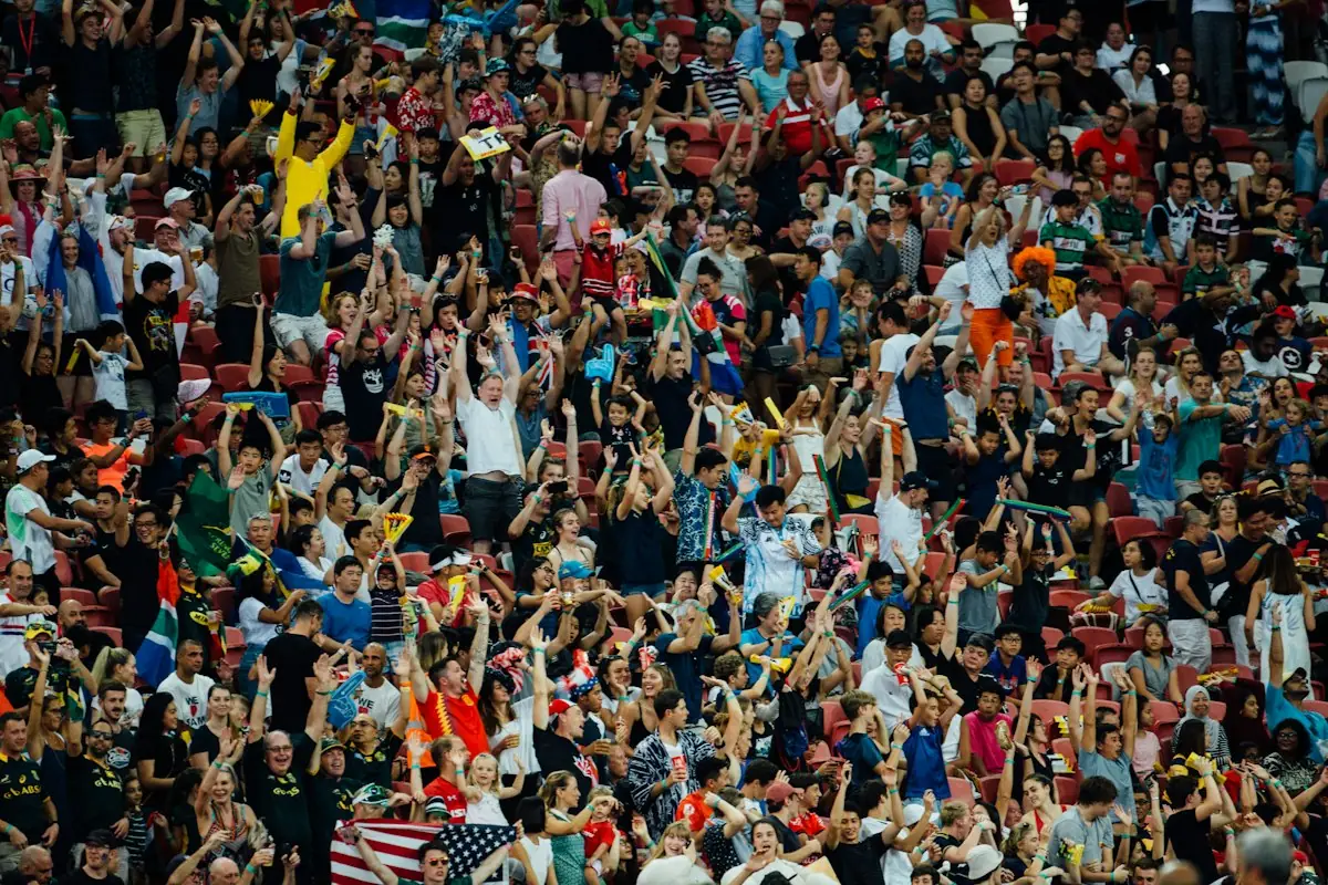 A stadium crowd cheering with arms raised