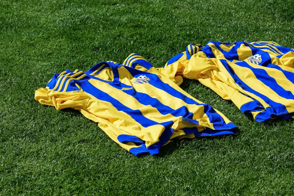 Yellow and blue striped football shirts laid on grass