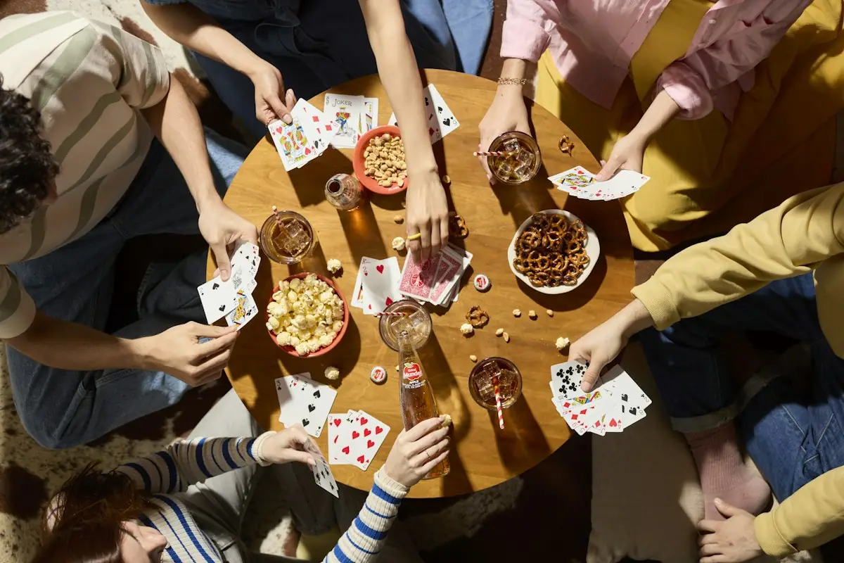 Friends playing cards around a table with snacks