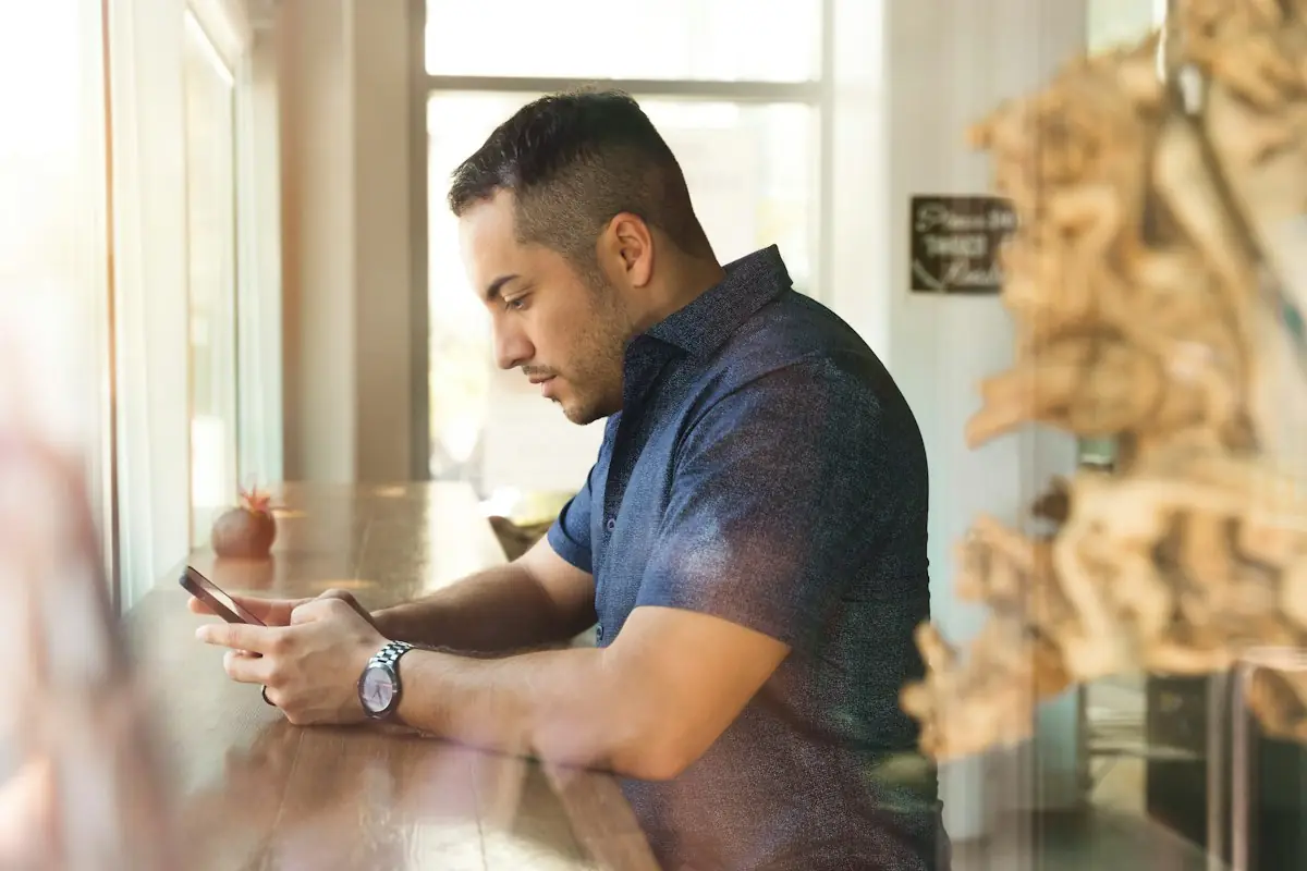 A man in a cafe checking prices on his phone