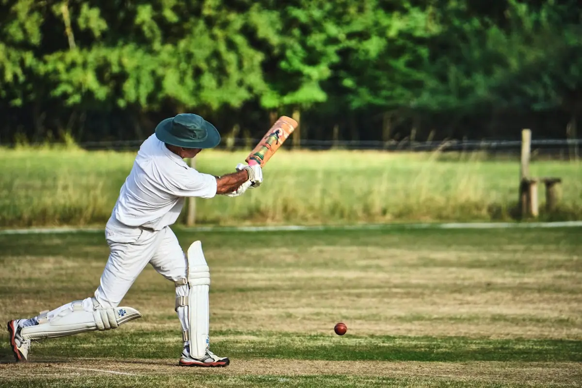 A batsman playing a shot on a village cricket pitch