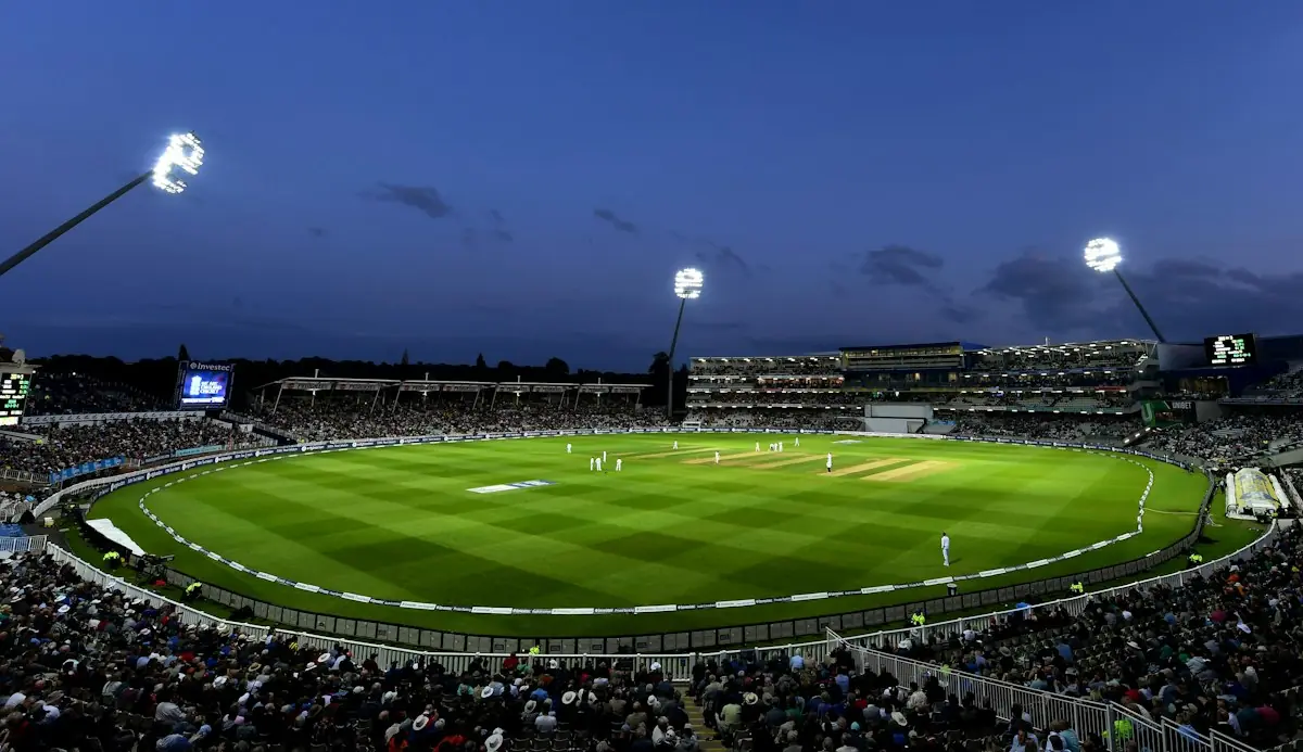 A floodlit cricket stadium at dusk