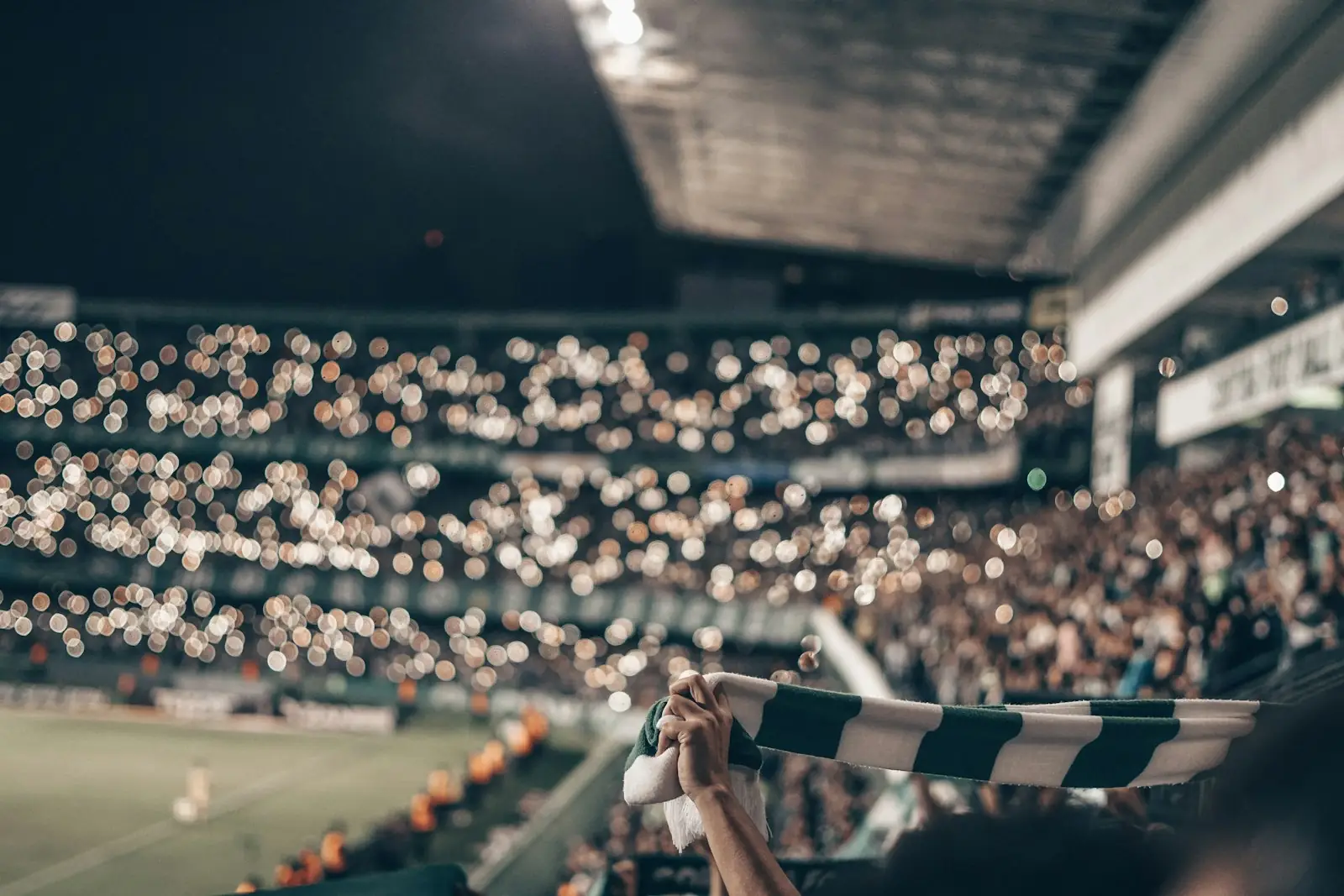 A stadium crowd at night waving a scarf