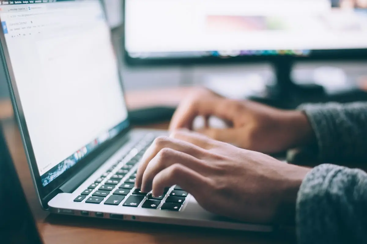 Hands filling in a form on a laptop
