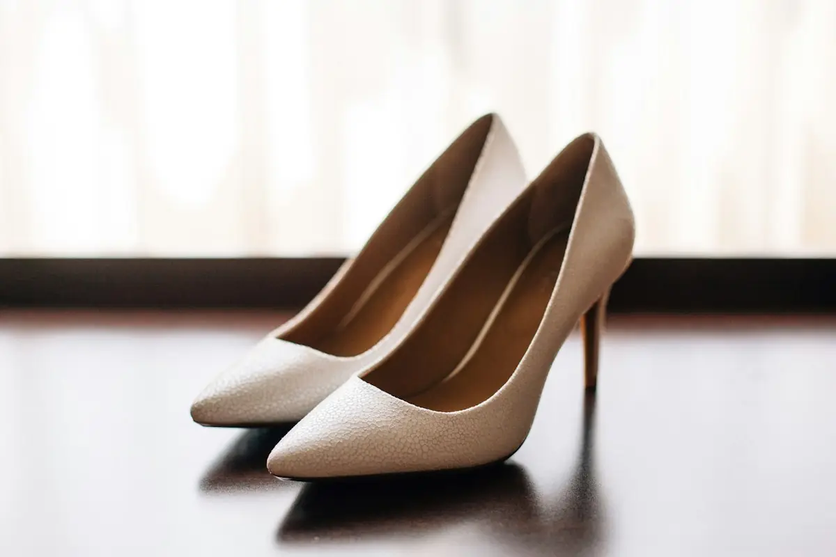 A pair of white high heels on a dark surface