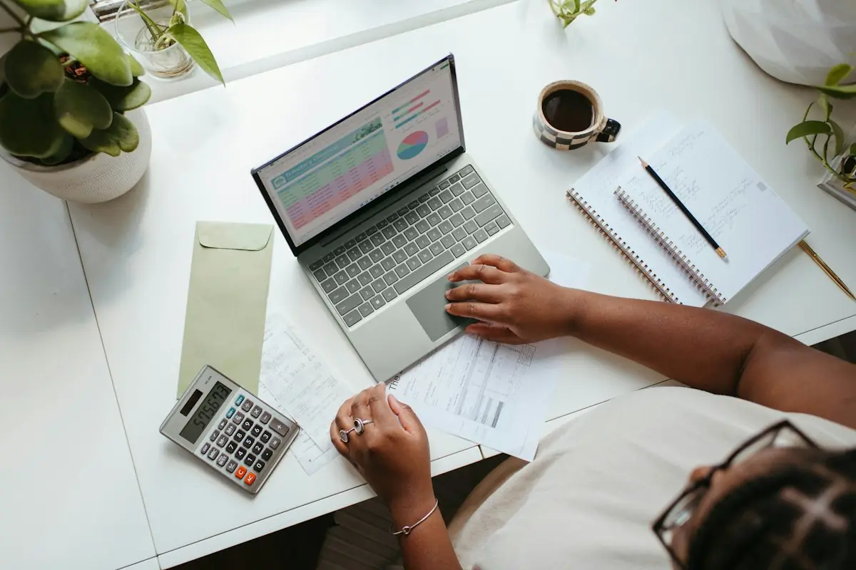 A woman working through her finances with a laptop and calculator