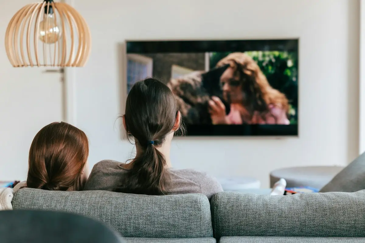 Friends watching television together on a sofa