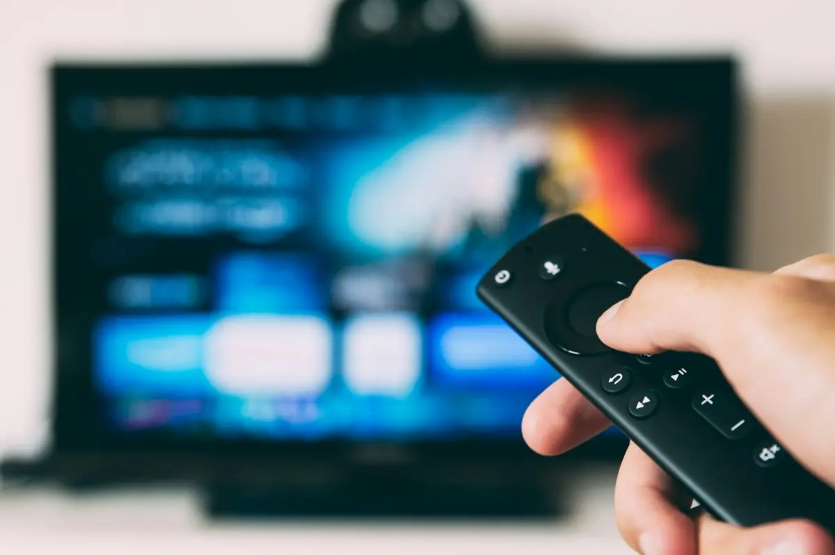 A hand pointing a remote at a television