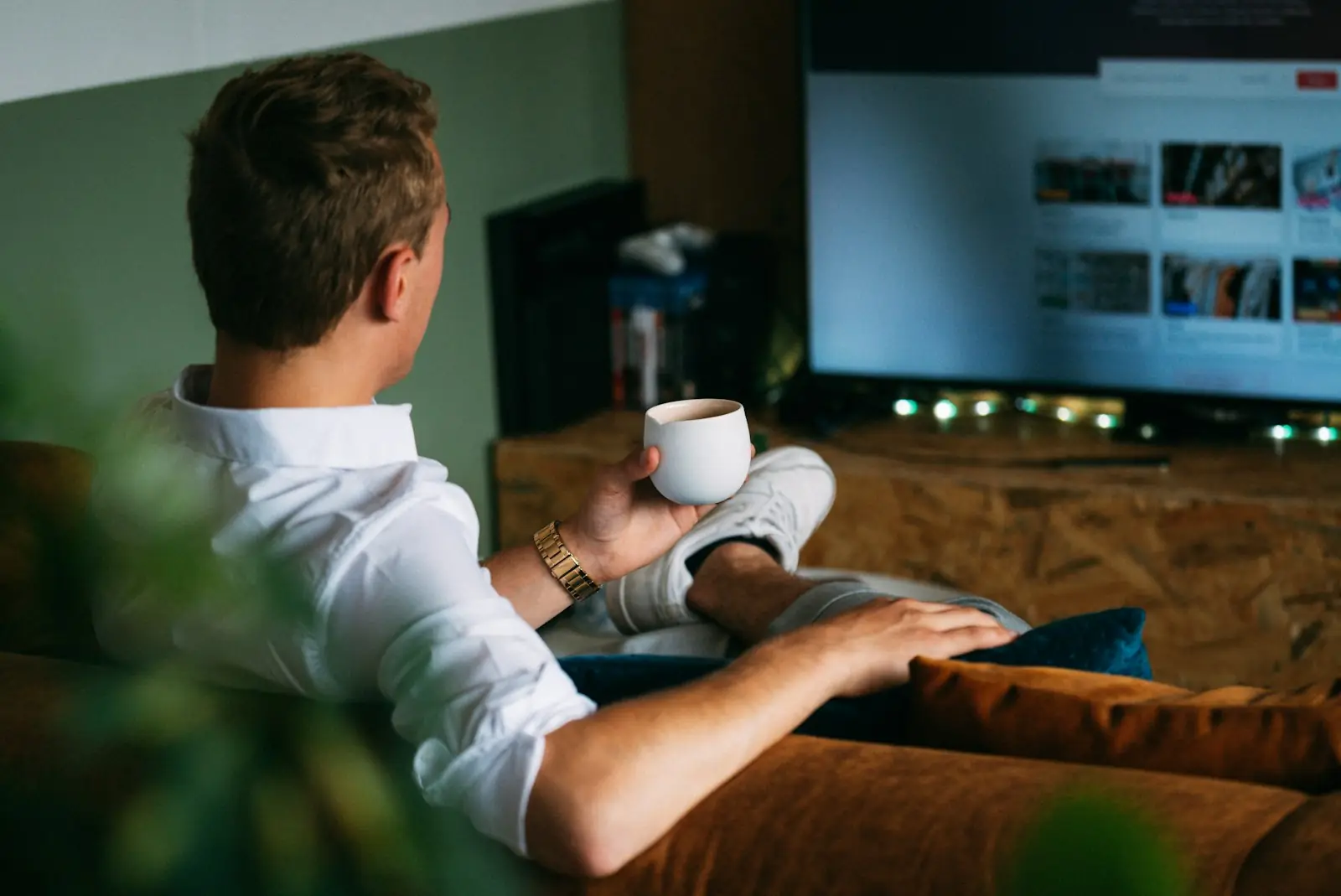 A man relaxing with a coffee in front of a screen