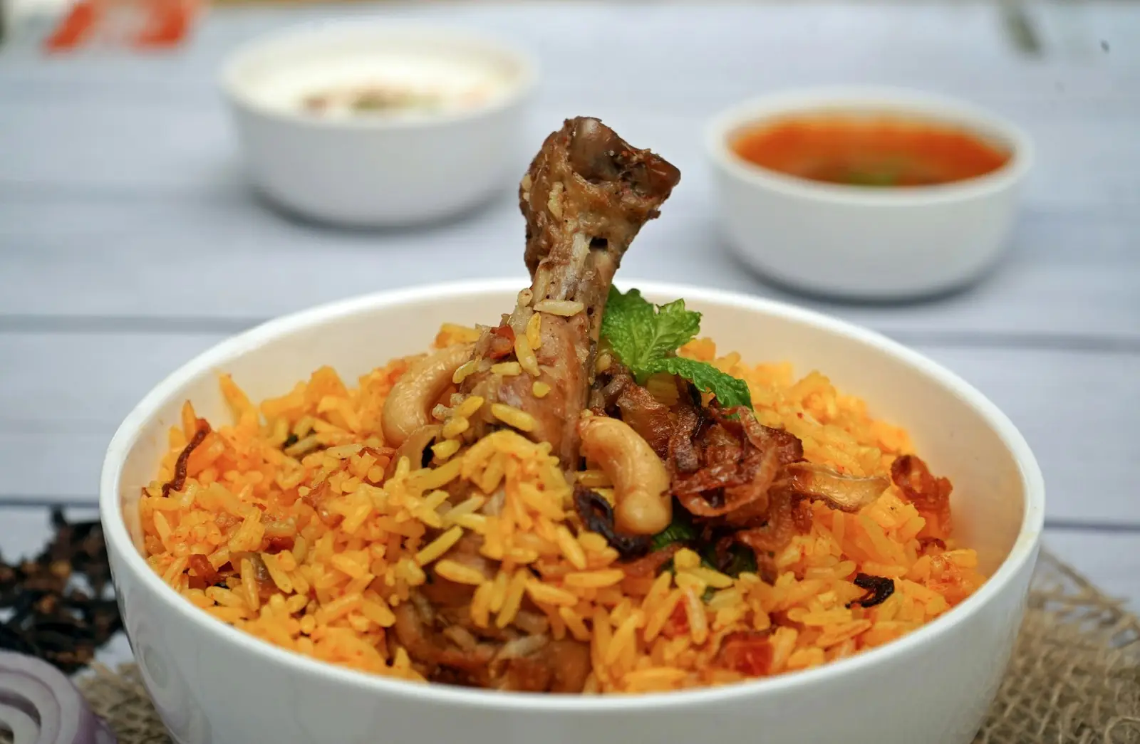 A bowl of chicken biryani with raita on the side
