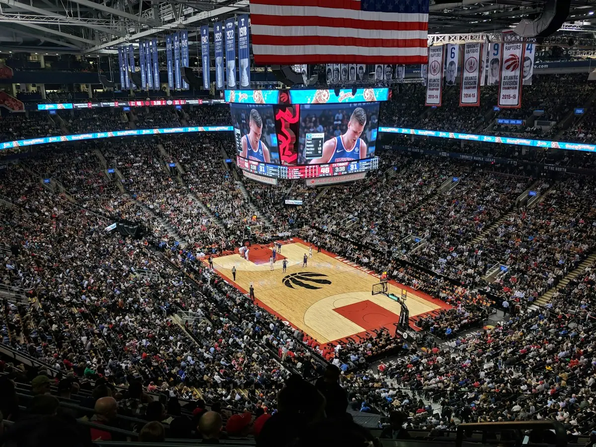 A packed basketball arena with the American flag above the court
