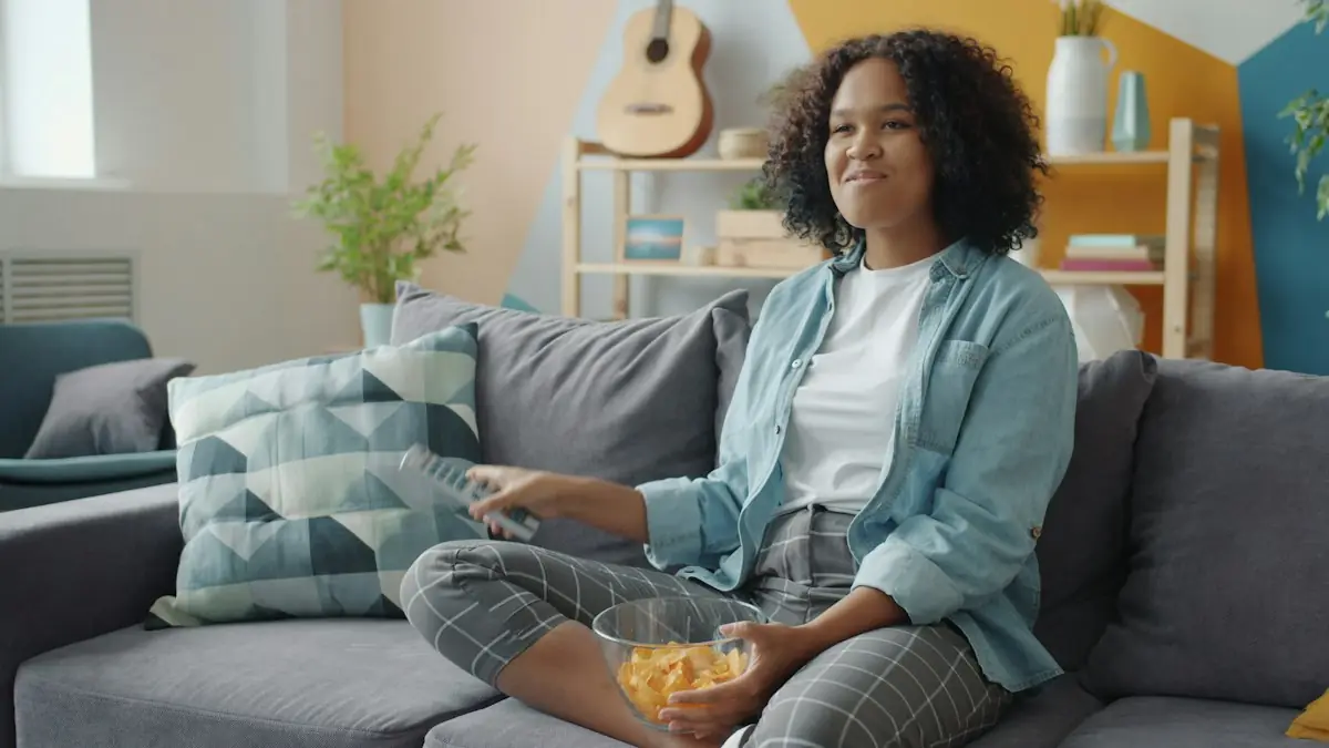 A woman watching sport on TV with snacks on the sofa