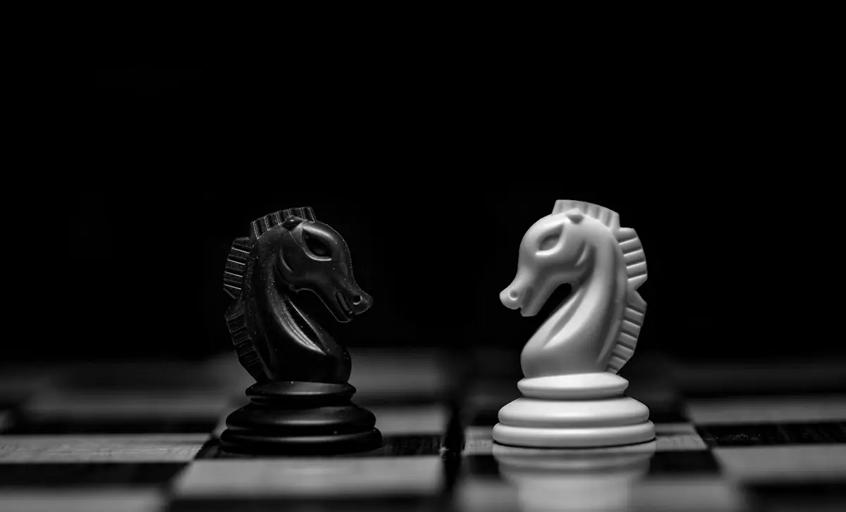 A black and a white chess knight facing each other