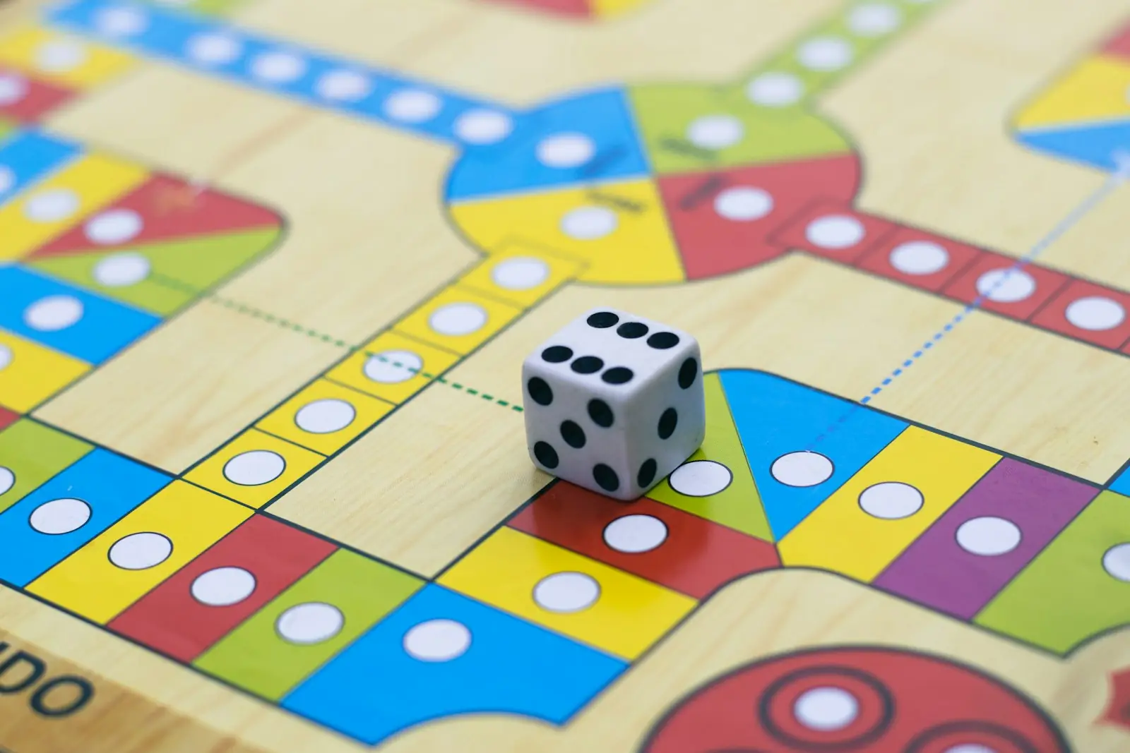 A die on a colourful ludo board